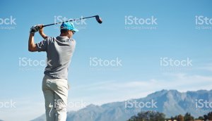 Golfer hitting tee shot with driver from tee-box, on beautiful course and good strike